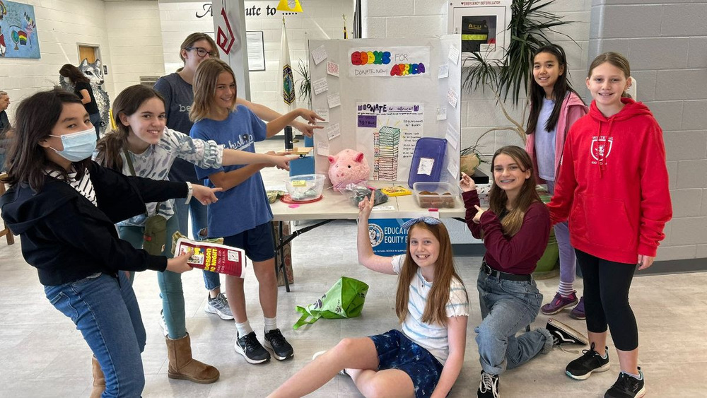 Henderson students pointing to their display they created explaining the Books for Africa book drive