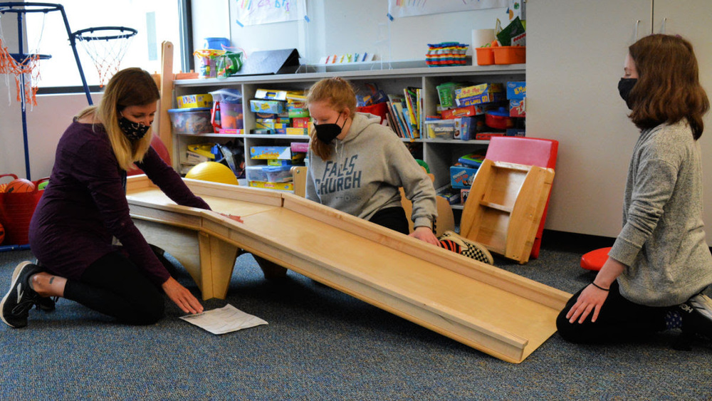 Three people assembing a scooter ramp
