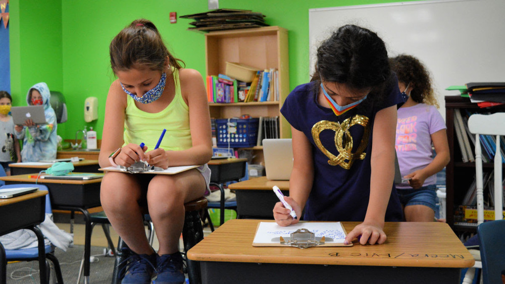 Two students writing poetry on clipboards