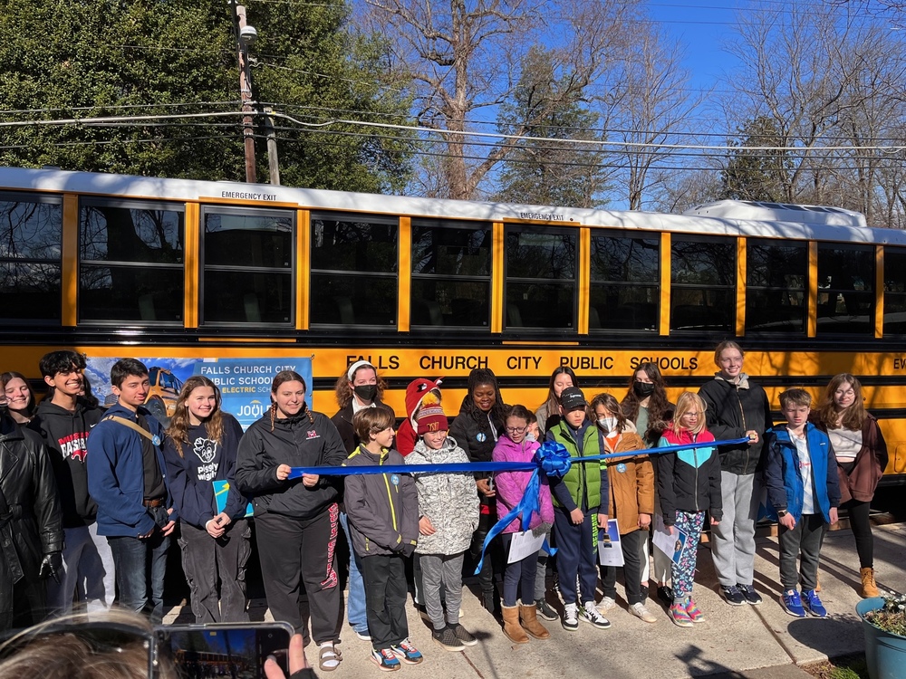 Students cut a blue ribbon to celebrate the arrival of two electric school buses