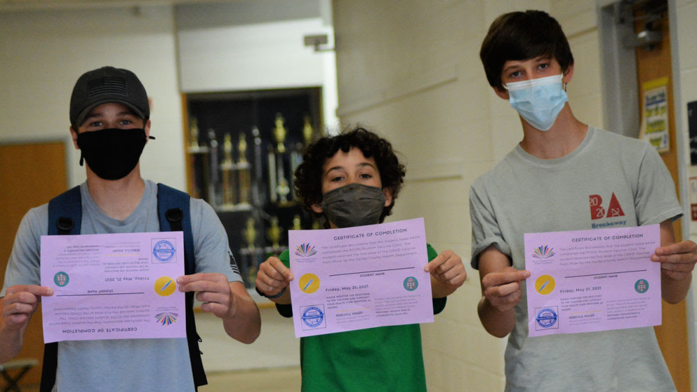 Students show certificates after receiving 1st dose of vaccine