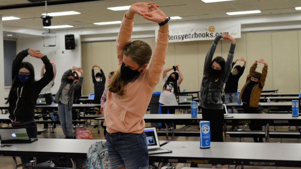 Students stretch at their tables before choir practice