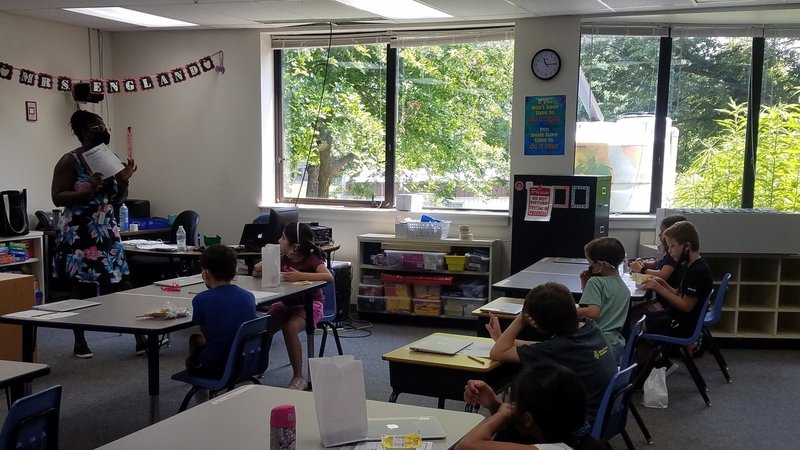 A teacher in front of her class explaining a worksheet they are about to work on.