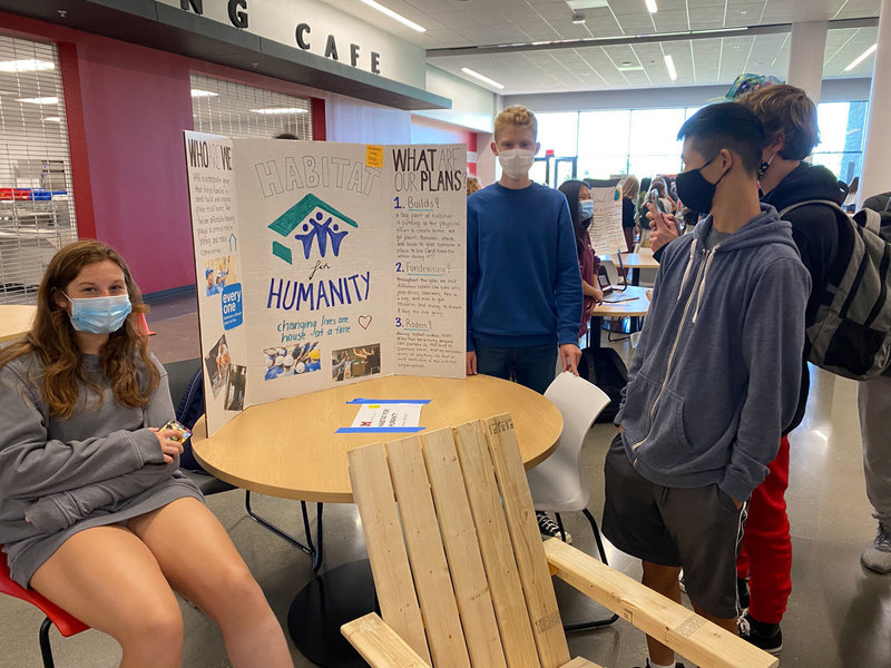 Students looking at the Habitat For Humanity Club display and description.