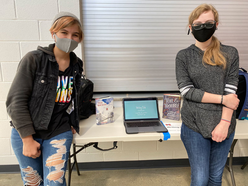 Two young ladies awaiting students to register for the Meridian Writing Club